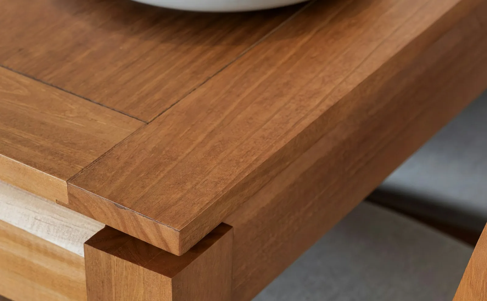 Close-up of a handcrafted wooden dining table corner with upholstered chairs tucked beneath